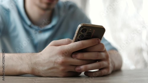 Close up shot of a businessman at work sitting on a table reading phone message or downloading an app for his mobile phone.
