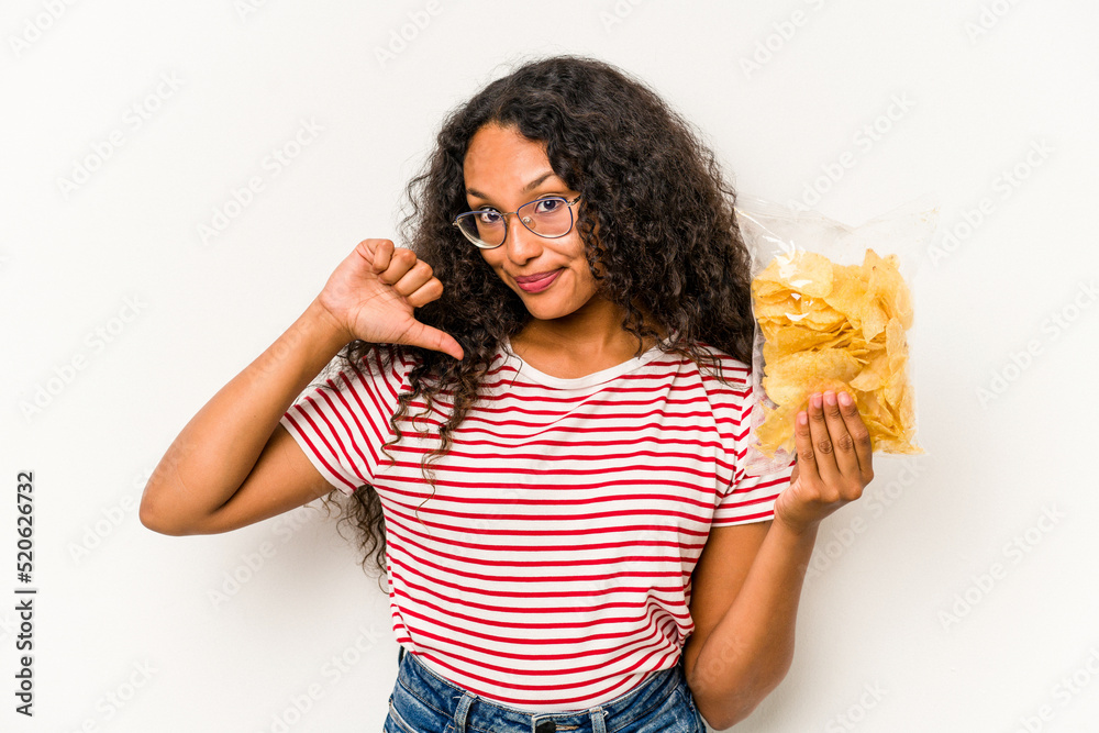 Young hispanic woman holding crips isolated on white background feels proud and self confident, example to follow.