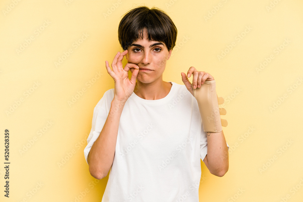 Young caucasian woman hand sling isolated on yellow background with fingers on lips keeping a secret.