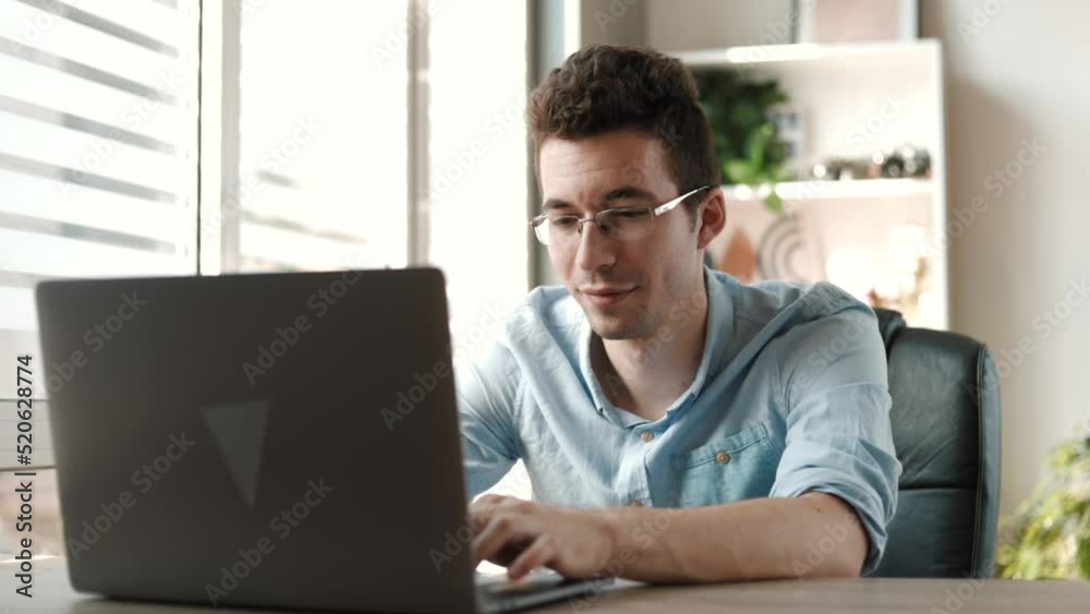 Smiling young businessman working on laptop computer at office. Male professional typing on laptop keyboard at office workplace. Portrait of positive business man looking at laptop screen indoors
Smiling young businessman working on laptop computer at office. Male professional typing on laptop keyboard at office workplace. Portrait of positive business man looking at laptop screen indoors