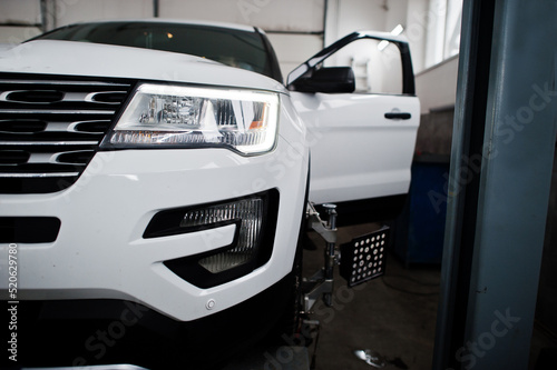 American SUV car on stand for wheels alignment camber check in workshop of service station.