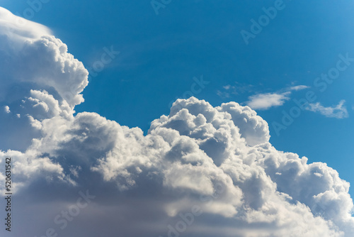 Big, fluffy clouds billowing and blowing in the blue sky 
