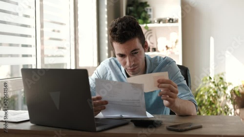 accountant doing calculation for online financial report at workplace. Serious man using calculator paying bill online holding paper sitting at home office desk. Accounting concept
