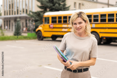 Portrait of positive middle aged woman teacher, psychologist, mentor, therapist, counselor near the school bus photo