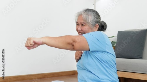 Asian elderly woman exercising at home Extend your arms forward. Social distancing. Health care of the elderly. sports concept photo