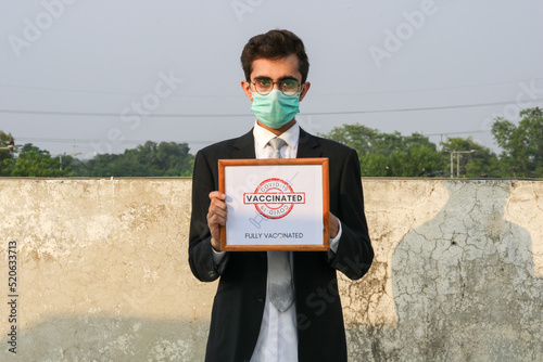 Covid 19 Certification Selective focus. Young Guy Holding Covid 19 Vaccination Certificate wearing face mask.
