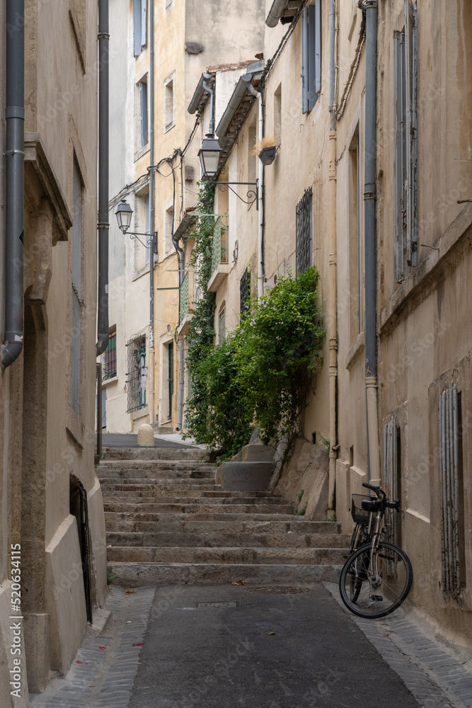Scenic urban landscape view of typical narrow street with ancient buildings, steps and bicycle in the historic center of Montpellier, France