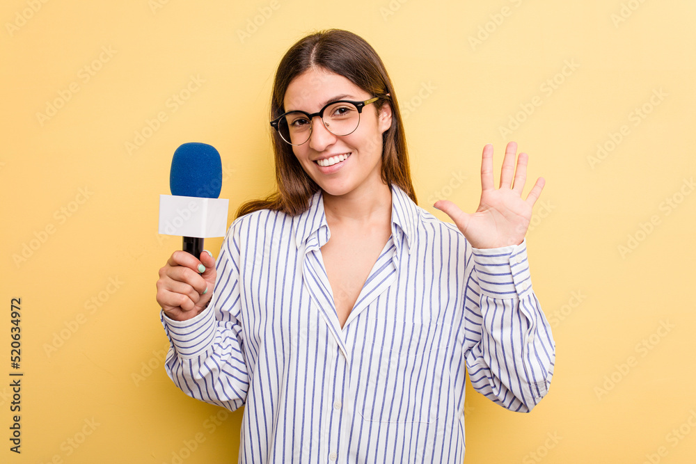 Young caucasian presenter TV woman isolated on yellow background smiling cheerful showing number five with fingers. Young caucasian presenter TV woman isolated on yellow background smiling cheerful showing number five with fingers.