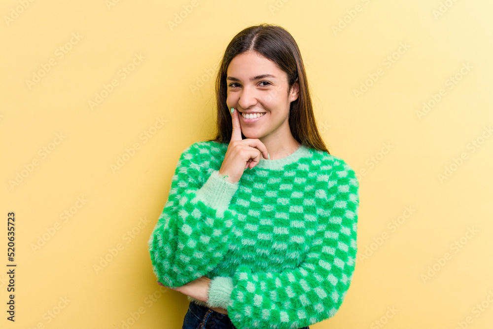 Young caucasian woman isolated on yellow background smiling happy and confident, touching chin with hand. Young caucasian woman isolated on yellow background smiling happy and confident, touching chin with hand.