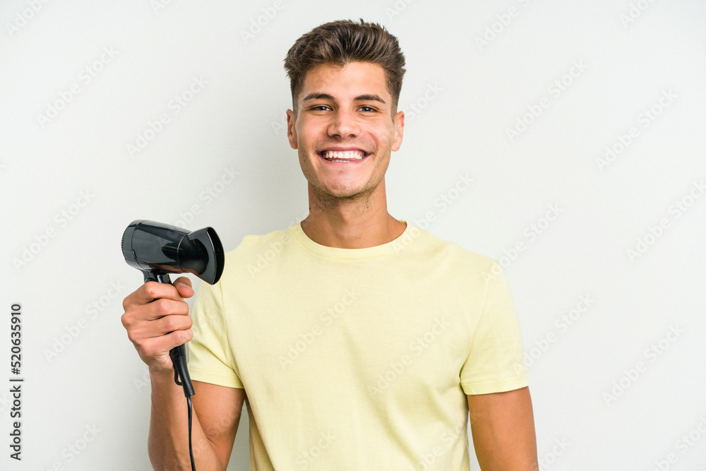 Young caucasian man holding hairdryer isolated on white background happy, smiling and cheerful. Young caucasian man holding hairdryer isolated on white background happy, smiling and cheerful.