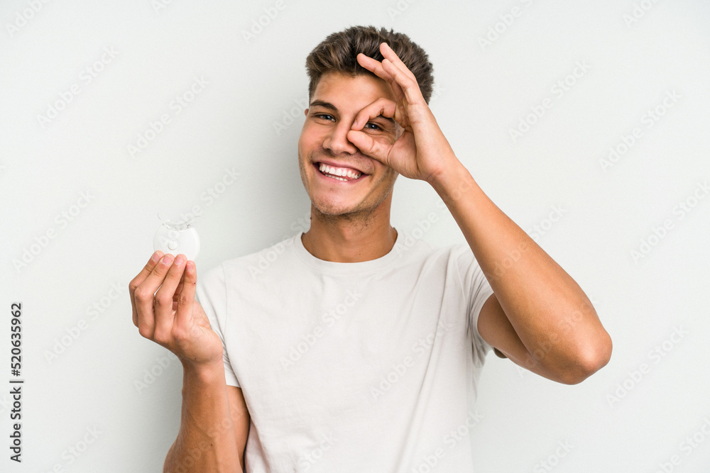 Young caucasian man hand sling isolated on white background excited keeping ok gesture on eye. Young caucasian man hand sling isolated on white background excited keeping ok gesture on eye.