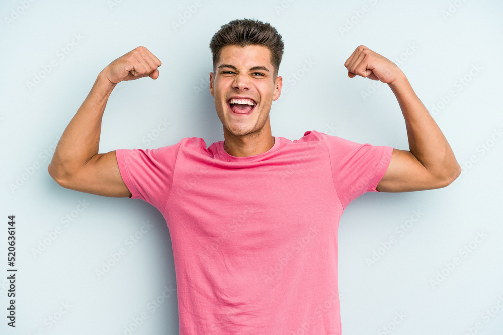 Young caucasian man isolated on blue background showing strength