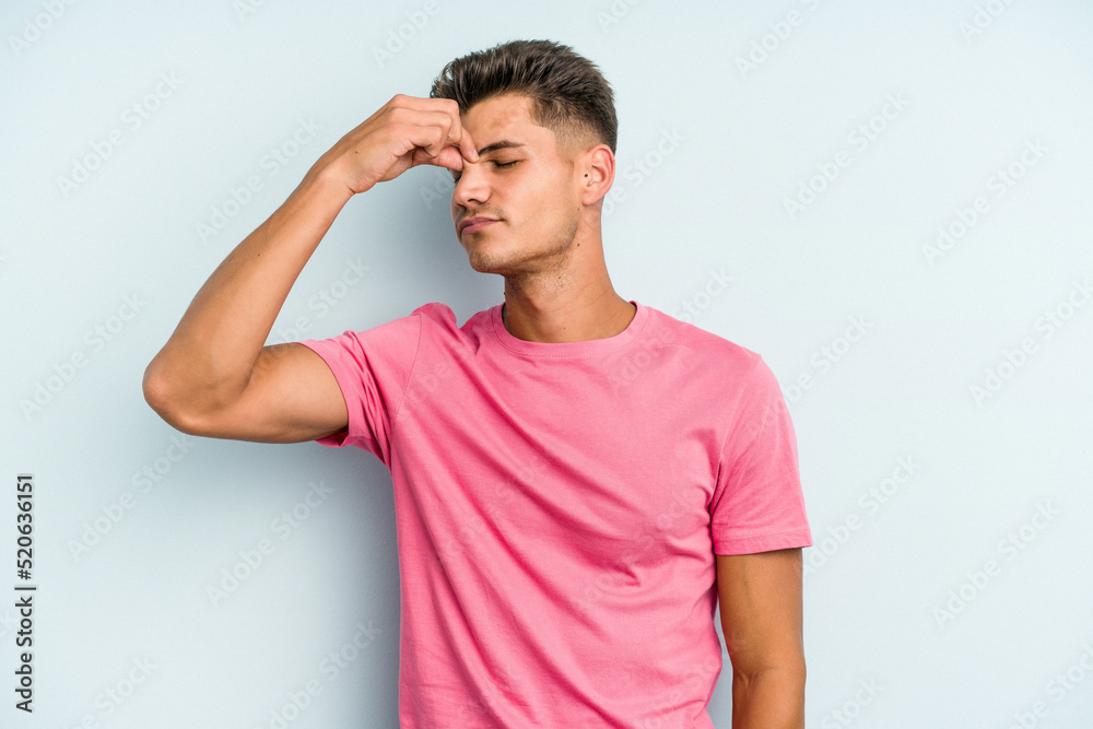 Young caucasian man isolated on blue background having a head ache, touching front of the face.