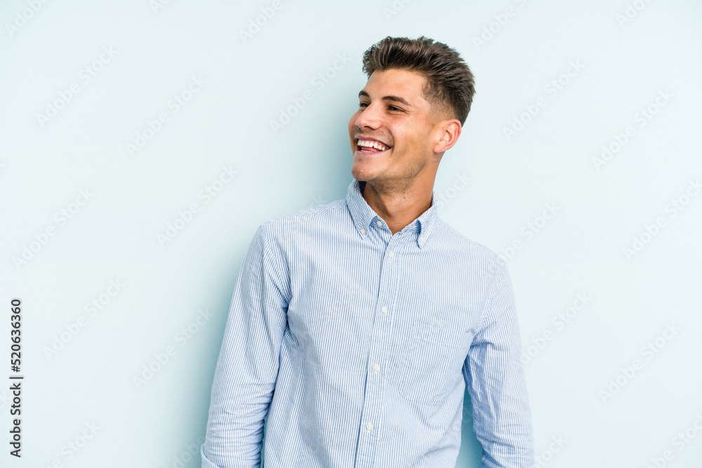 Young caucasian man isolated on blue background relaxed and happy laughing, neck stretched showing teeth.
