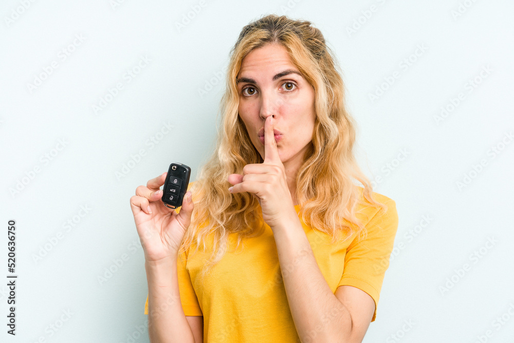 Young caucasian woman holding car keys isolated on blue background keeping a secret or asking for silence. Young caucasian woman holding car keys isolated on blue background keeping a secret or asking for silence.