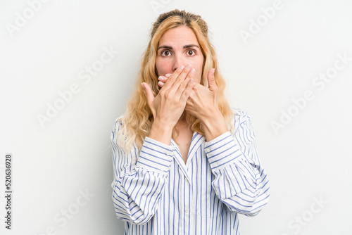 Young caucasian woman isolated on white background shocked covering mouth with hands. © Asier