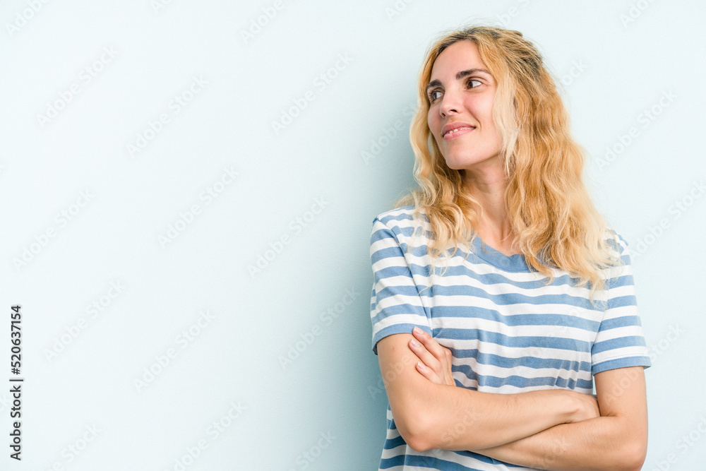 Young caucasian woman isolated on blue background smiling confident with crossed arms. Young caucasian woman isolated on blue background smiling confident with crossed arms.
