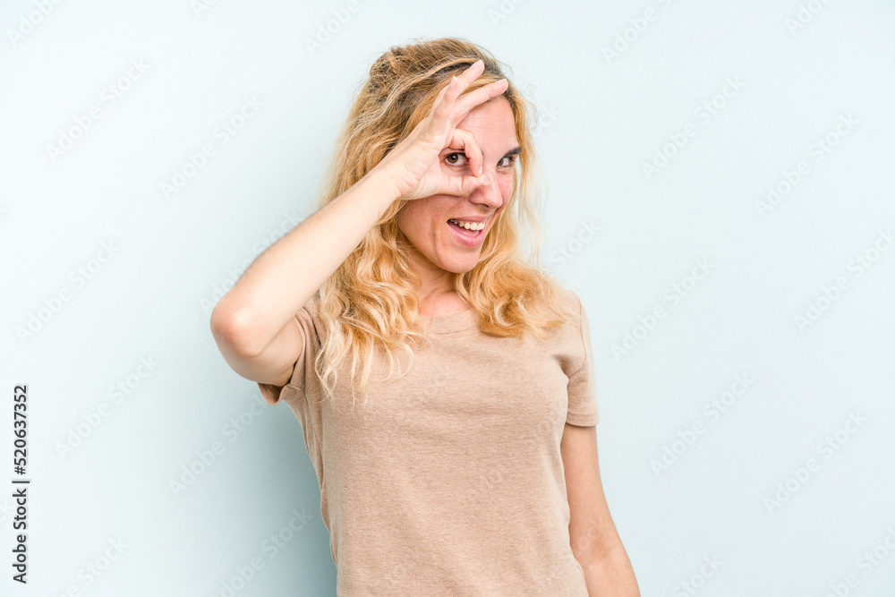 Young caucasian woman isolated on blue background excited keeping ok gesture on eye.