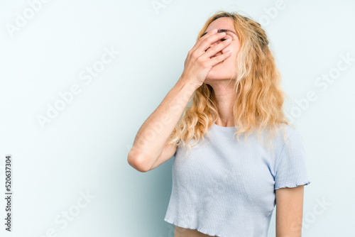Young caucasian woman isolated on blue background laughing happy, carefree, natural emotion.