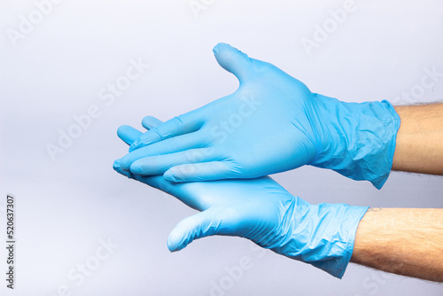 two human hands in blue nitrile surgical gloves, professional medical safety and hygiene for surgery and medical examination on a white background. Lots of empty space © Nyaaka