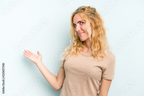 Young caucasian woman isolated on blue background showing a welcome expression.