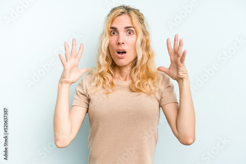 Young caucasian woman isolated on blue background celebrating a victory or success, he is surprised and shocked.