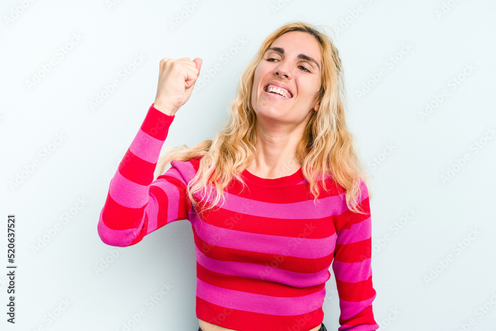Young caucasian woman isolated on blue background celebrating a victory, passion and enthusiasm, happy expression.