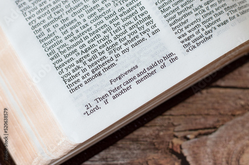 "Forgiveness" word in an open Holy Bible Book placed on a wooden table. A close-up. 