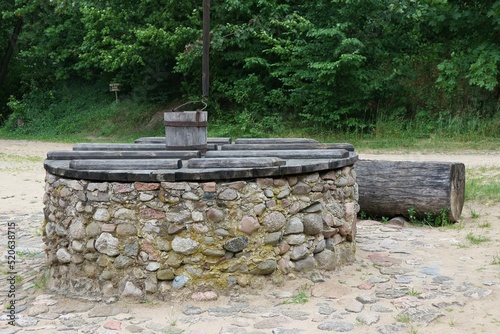 An old stone well covered with a wooden lid with a wooden bucket hanging over it.