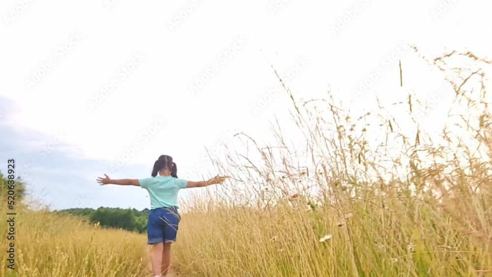 Happy little girl runs among the tall grass, in a field, in summer Happy little girl runs among the tall grass, in a field, in summer