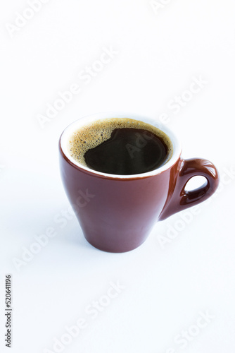 Black coffee in the brown cup on the white background. Closeup. Location vertical.