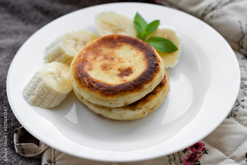 two cottage cheese pancakes with sliced banana in a white plate
