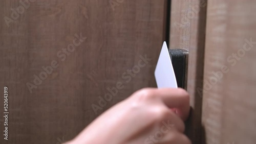 Woman hand puts key card to panel opening hotel room door. Female person with blue nails opening door walks in room on blurry background closeup photo