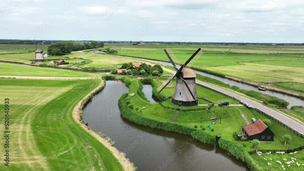 Historic traditional typical dutch old windmills mills on the rural countryside in green nature grass field farm landscape with a river sunny weather. Tourist attraction.