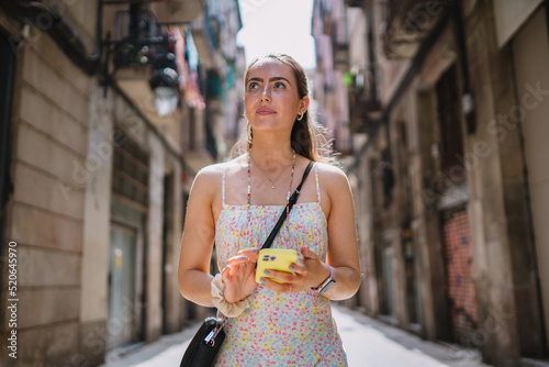 Happy female tourist phone user walking in old town alley an using smartphone. GPS maps, concept. Barcelona, Spain. photo
