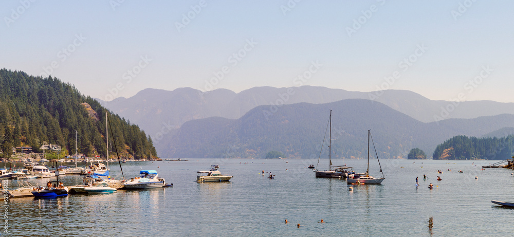 Leisure craft moored at Deep Cove, BC, a popular venue for paddleboarders and kayakers, on a sweltering summer day.