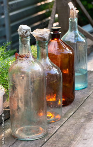Several old and dirty glass bottles on a wooden table outside in the village