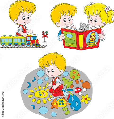 Happy little girl and boy reading a book, playing with a toy train and drawing with color crayons