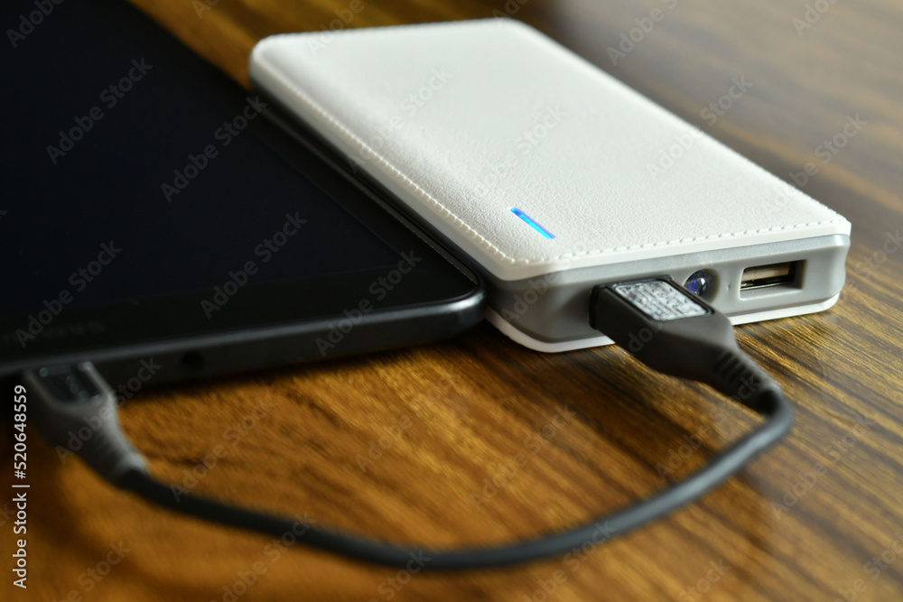 Tableta conectada a un cargador portatil por medio de cable. Concepto de Tecnologia, toma lateral. Tableta conectada a un cargador portatil por medio de cable. Concepto de Tecnologia, toma lateral.