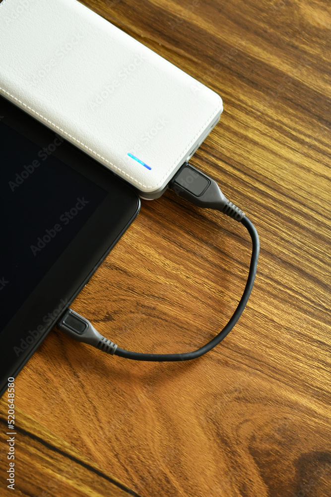 Tableta conectada a un cargador portatil por medio de cable. Concepto de Tecnologia, toma cenital. Tableta conectada a un cargador portatil por medio de cable. Concepto de Tecnologia, toma cenital.
