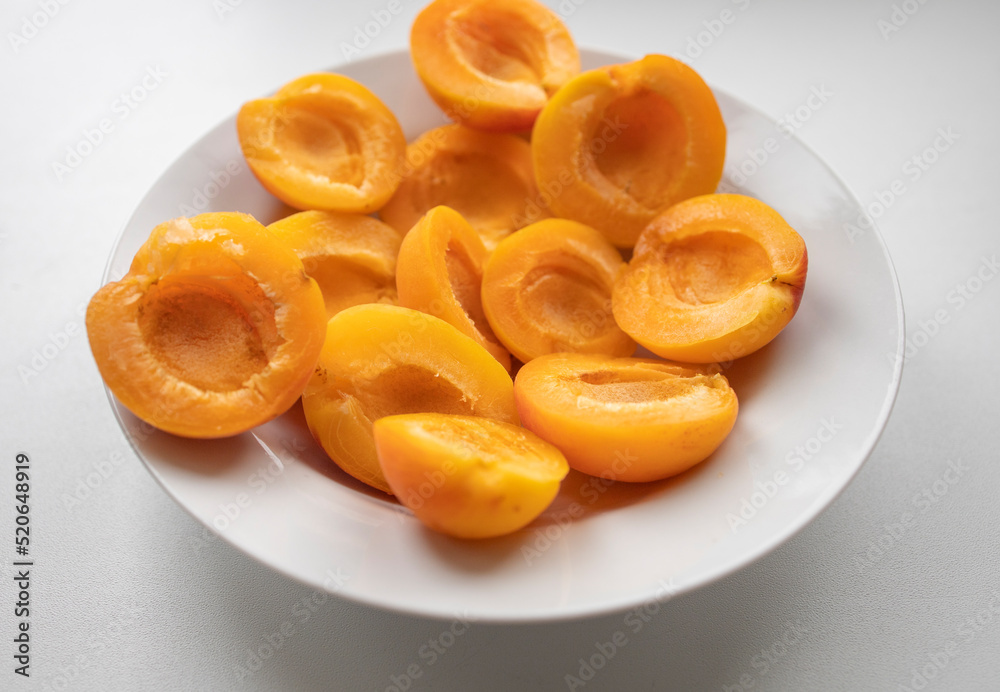 ripe, juicy apricots lie on a white plate. Energy boost, vitamins, ripe fruits, pesticides. Interruptions in the supply of fruits, imports of apricots