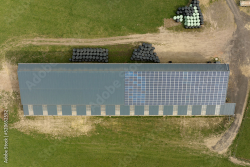 Aerial view of farm building with photovoltaic solar panels mounted on rooftop for producing clean ecological electricity. Production of renewable energy concept