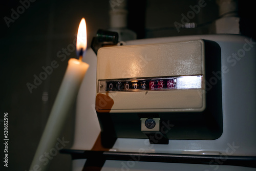 A man with a burning candle checks the gas meter. Gas crisis and lack of energy resources. Save energy and use candles instead of electricity. Checking home energy meters photo