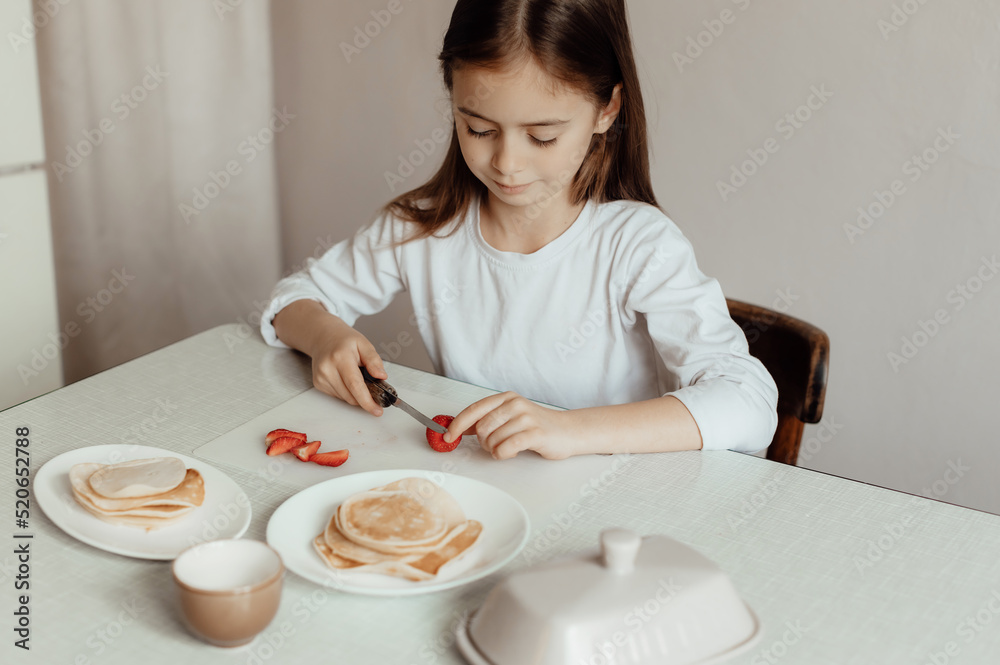 Hungry little girl eat sweet panckaces with strawberries. Family breakfast concept Hungry little girl eat sweet panckaces with strawberries. Family breakfast concept
