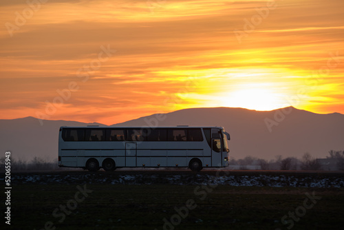 Intercity passenger bus driving on highway road in evening