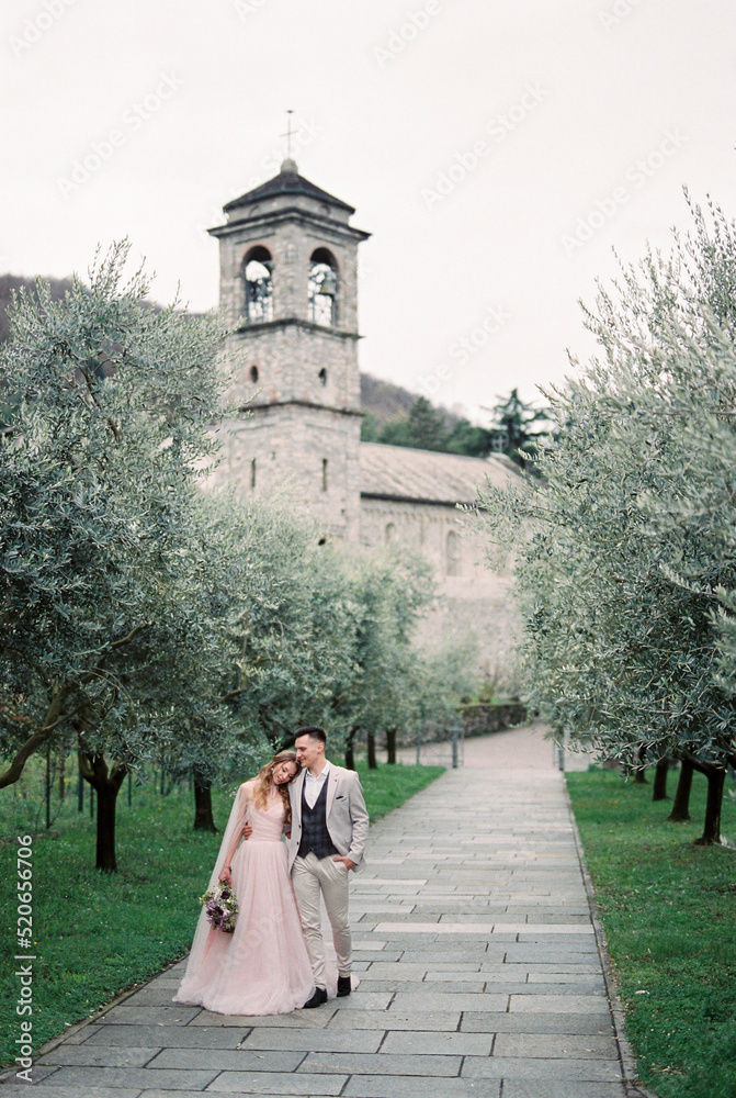 Bride and groom stand on the path in the olive grove. Como, Italy