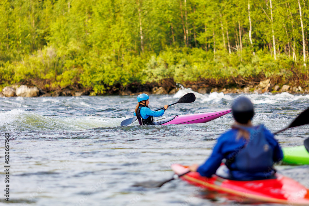Obraz premium Whitewater kayaking, extreme sport rafting. Young woman in kayak sails mountain river