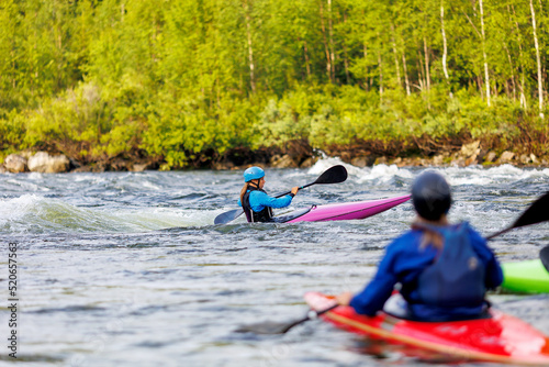Whitewater kayaking, extreme sport rafting. Young woman in kayak sails mountain river