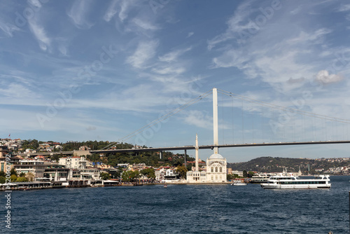 View of cruise tour boats on Bosphorus, historical Ortakoy mosque and bridge in Istanbul. It is a sunny summer day. Beautiful scene.