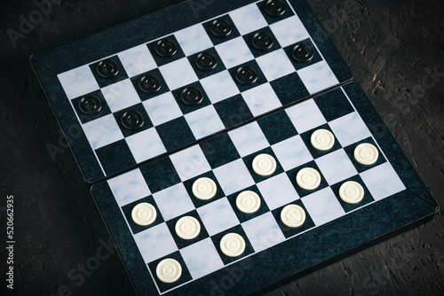 Checkers board with chips black background, checkers logical board game.
